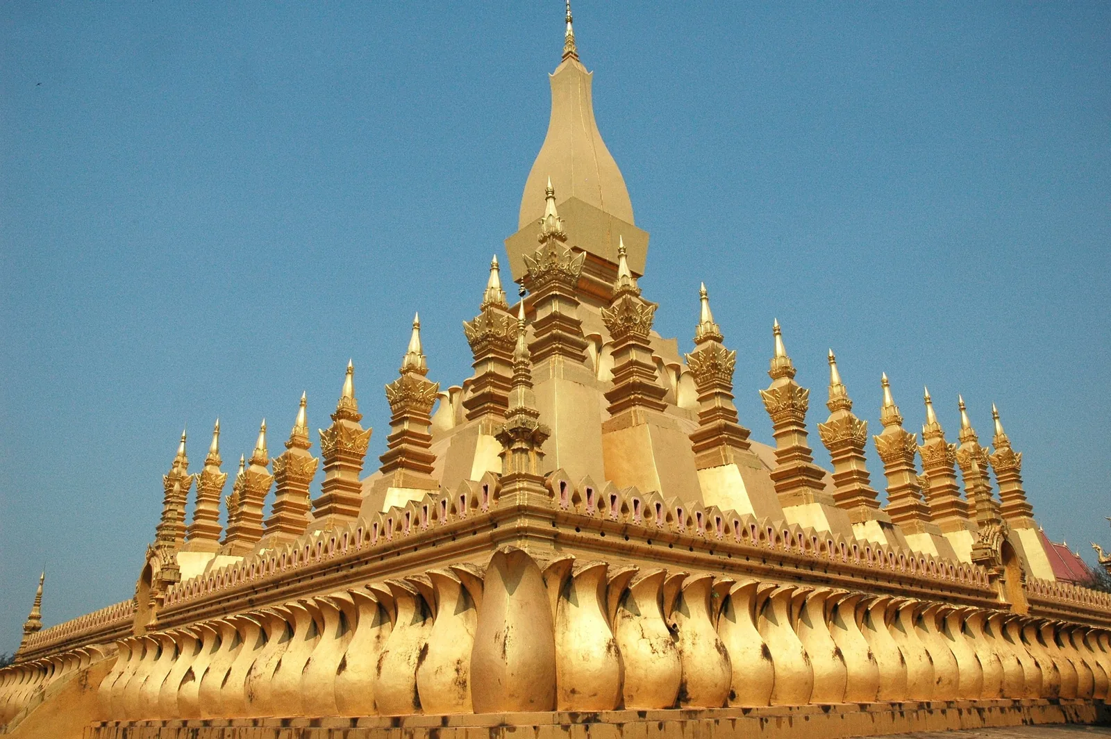 Golden tiered spires of Pha That Luang stupa rise against a clear blue sky in Vientiane.