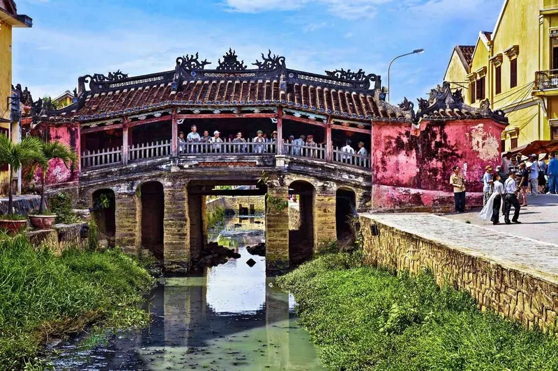 The iconic Japanese Covered Bridge with its curved tiled roof spans a narrow canal in Hoi An's ancient town.
