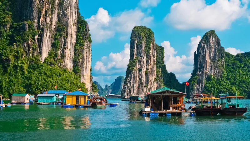 Floating fishing village houses sit among towering limestone karsts in Halong Bay.