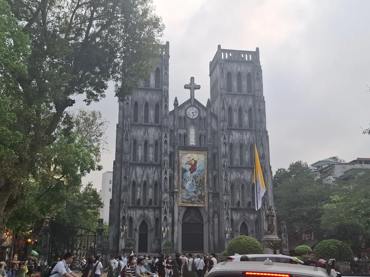 The twin Gothic towers of St. Joseph's Cathedral rise above a crowd gathered on the street in Hanoi's Old Quarter.