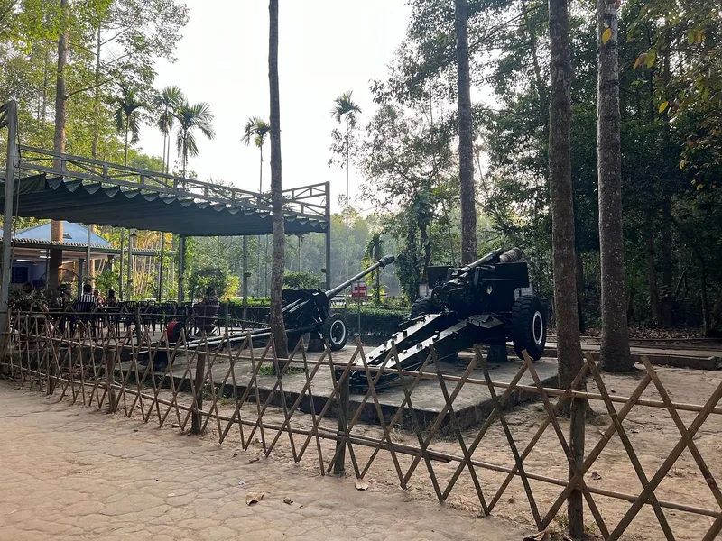 Old military artillery guns displayed under a shaded canopy at a wartime relics site in Saigon, Vietnam.