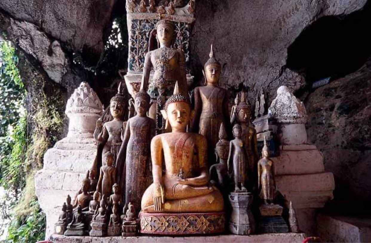 Rows of small Buddha statues left by pilgrims inside a riverside cave shrine