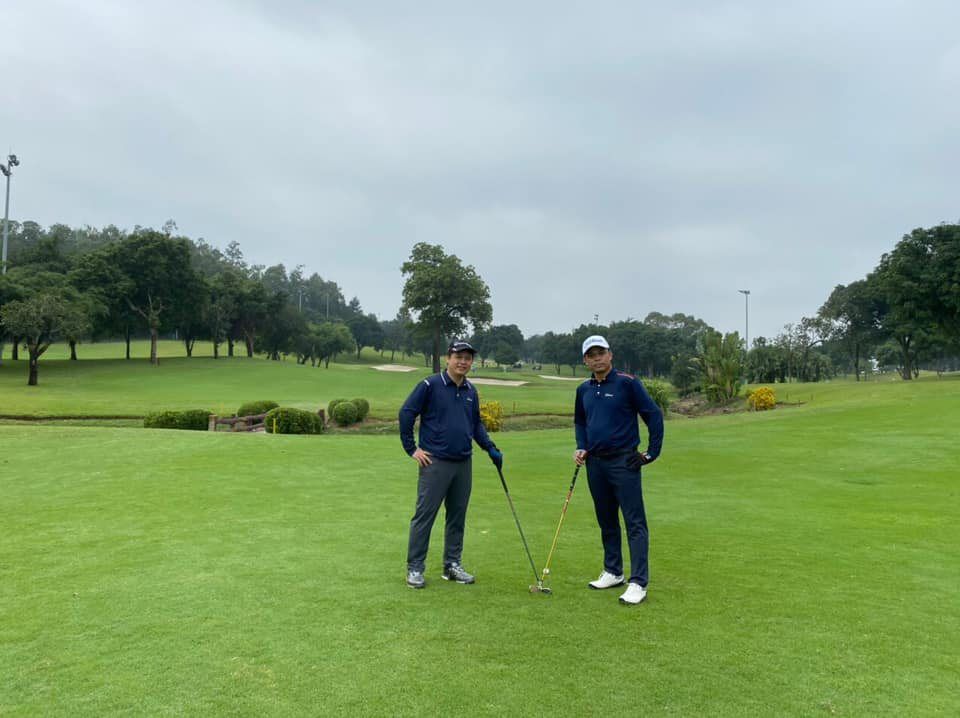 Two golfers walking a fairway on a tropical course