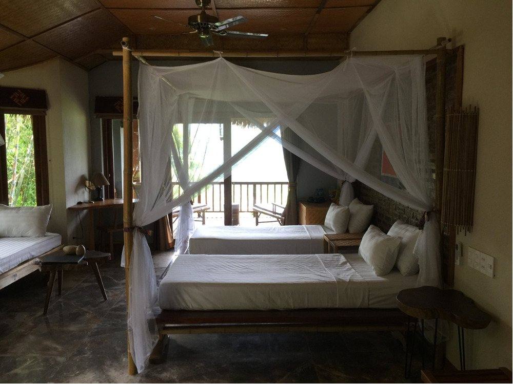 Simple bedroom with a four-poster mosquito net and open shutters