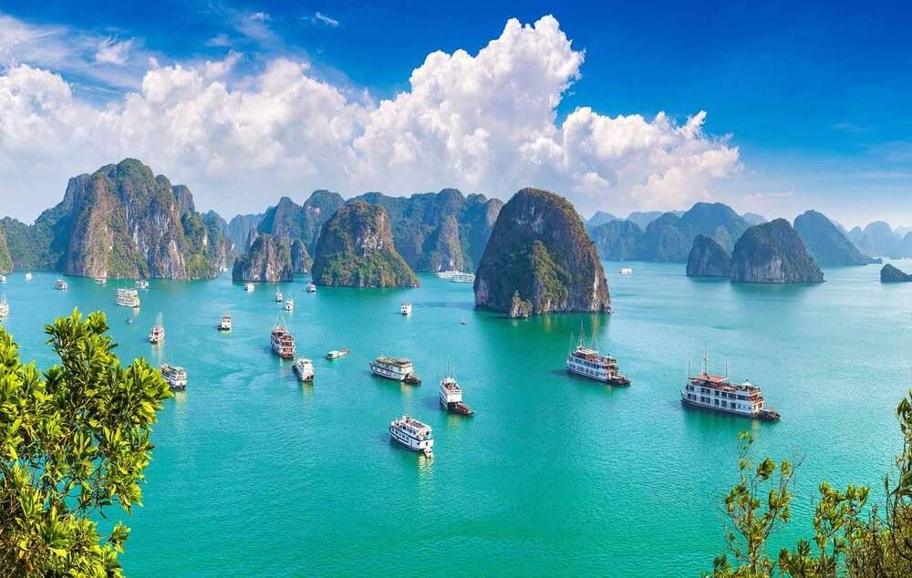 Cruise boats among the limestone islands under bright cloud
