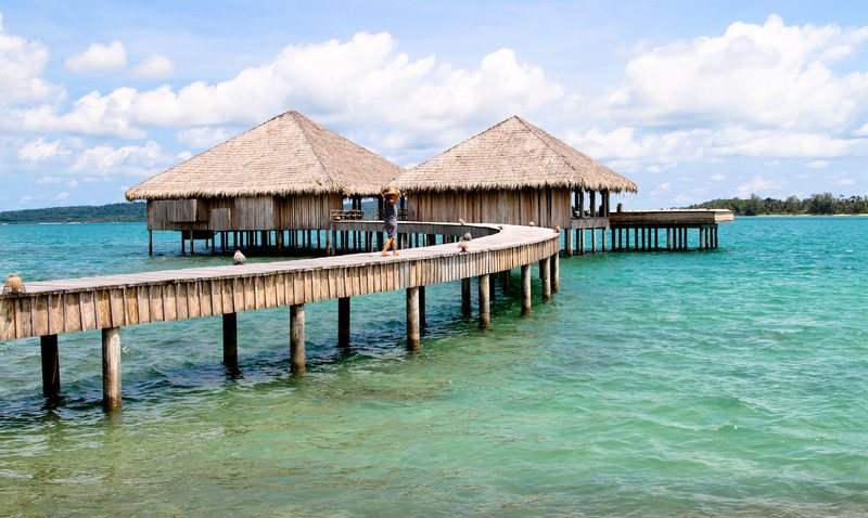 Thatched overwater bungalows on a jetty above clear shallow water