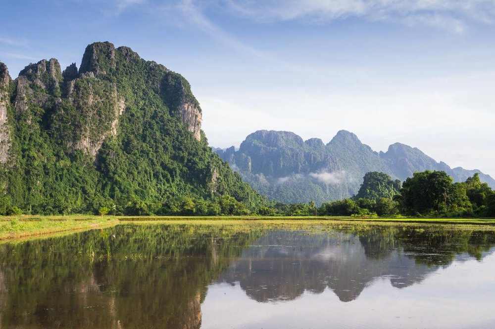 Limestone cliffs reflected in a still river in central Laos