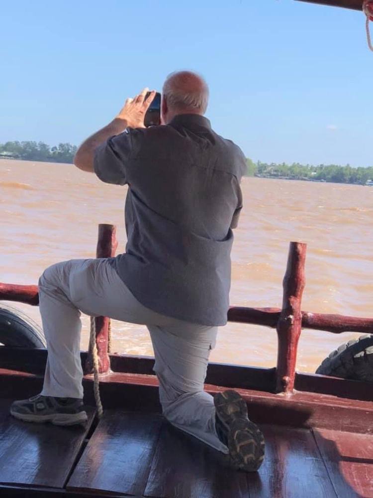 Traveller photographing the river from the deck of a wooden boat