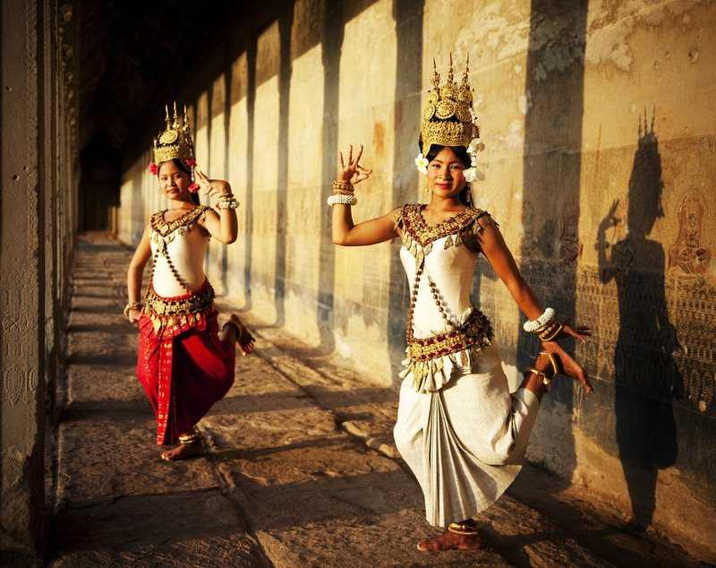 Apsara dancers posing in the stone gallery of an Angkor temple