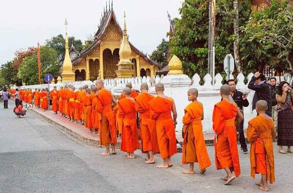 Line of monks collecting alms along a street at dawn