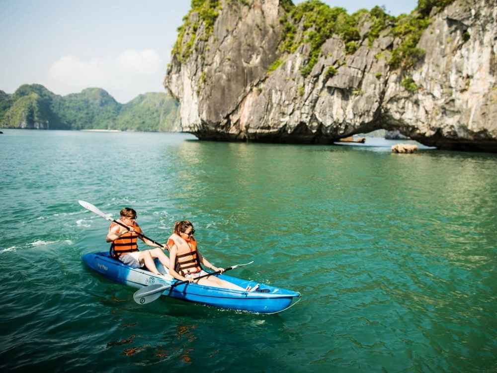 Kayakers paddling between limestone cliffs in Ha Long Bay
