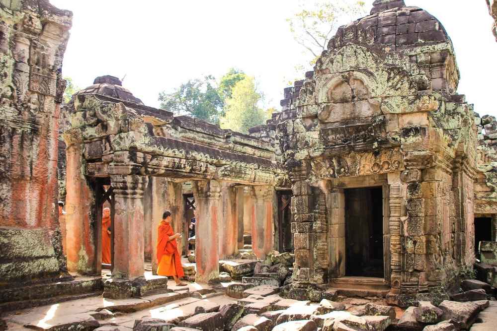 Monk walking past the carved stone doorway of an Angkor temple