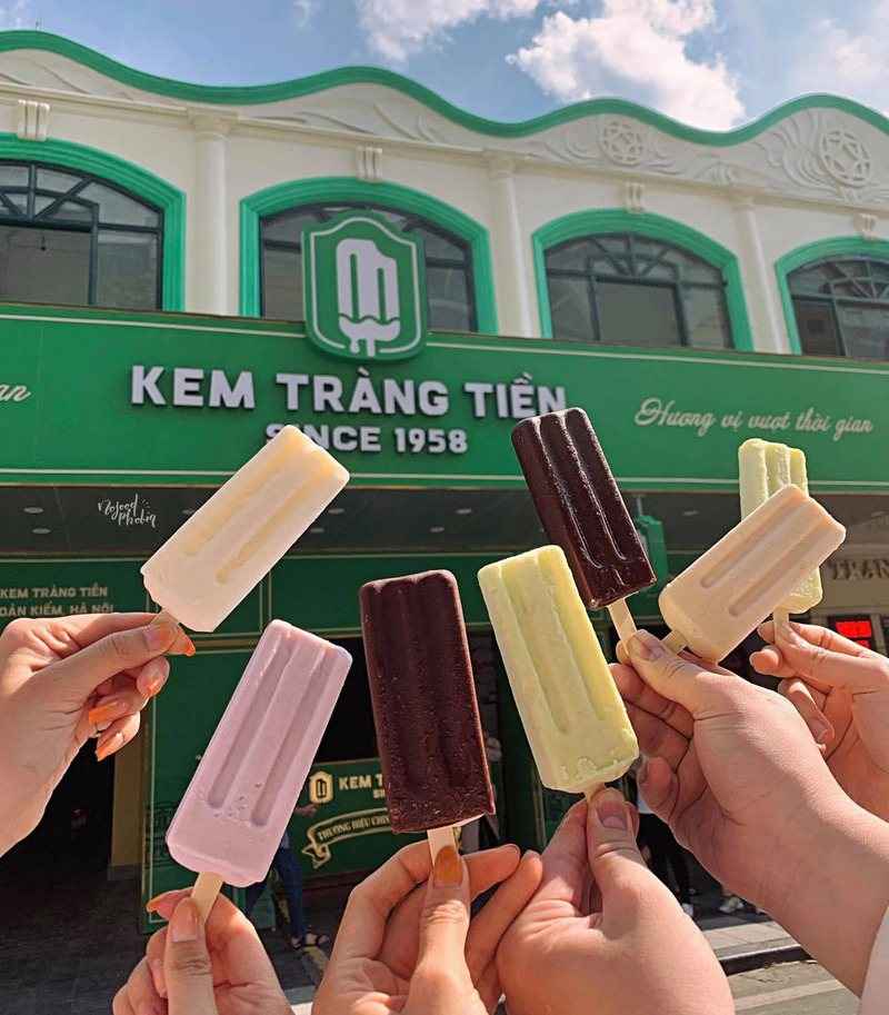Hands holding pastel ice-cream bars outside a Hanoi ice-cream shop