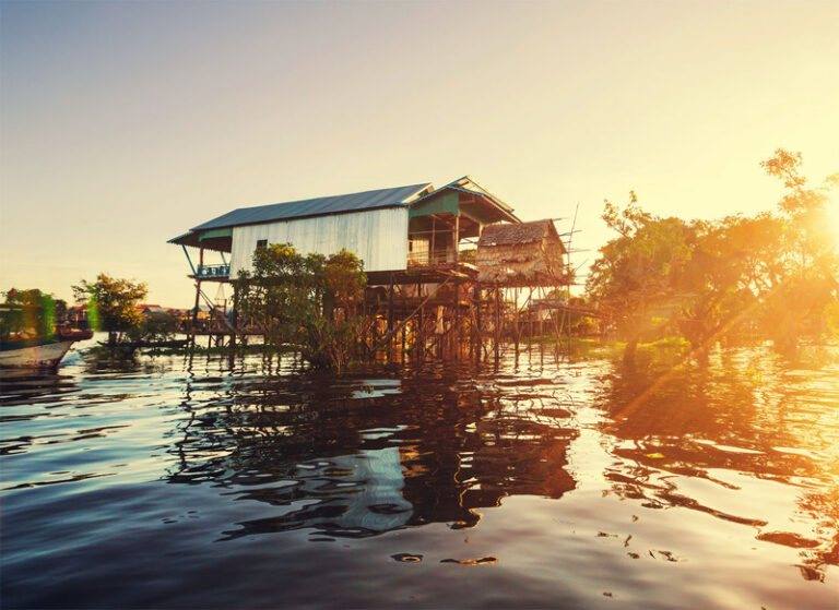 Stilt house glowing over the water at sunset