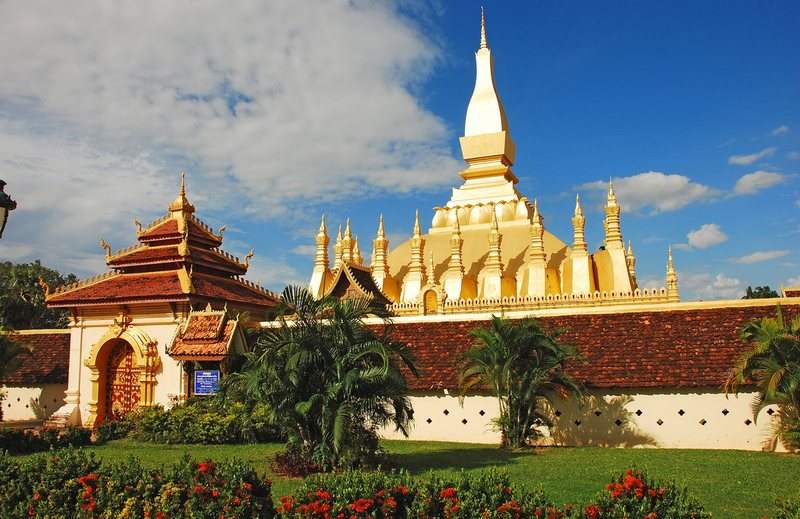 Pha That Luang stupa behind tropical gardens in Vientiane