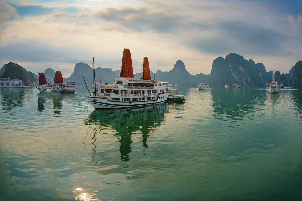 Red-sailed junk cruising among the islands of Ha Long Bay